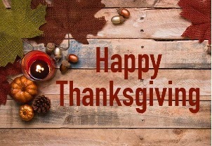 The words Happy Thanksgiving with a wooden table with a candle and various gourds in the background.