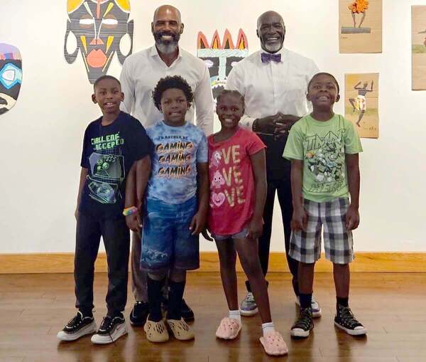 Two adults and four children are posing and smiling for the camera.