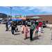 A group of individuals walking around the parking lot with blue pop up canopies in the background.