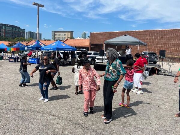 A group of individuals walking around the parking lot with blue pop up canopies in the background.