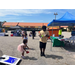 A little girl trying to play corn hole while a young man walks in front of her.