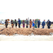 Twelve individuals with shovels in a line while throwing dirt into a pile at the Commerce Ground Breaking Ceremony.