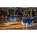 A big room full of individuals mingling around dinning tables.