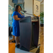 A close up of a woman in a blue dress speaking behind the podium.