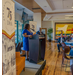 A woman in a blue dress speaking at a podium while the crowd smiles and laughs.