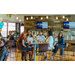 Individuals sitting at square bar top tables listening to a speaker.