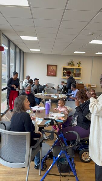 A room full of individuals sitting around tables doing arts and crafts.